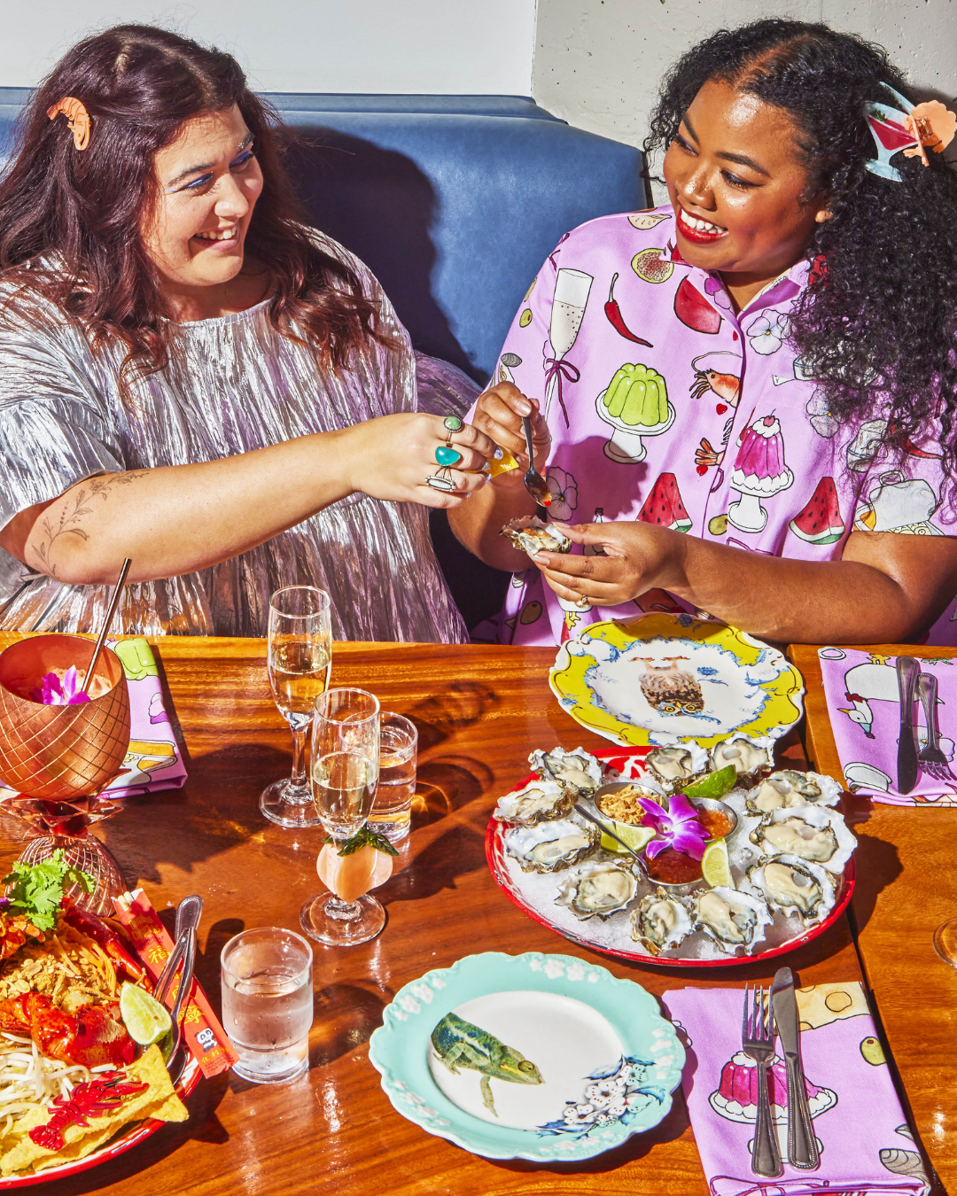 Models angelina and erin eating oysters and wearing metallic top and dinner party print