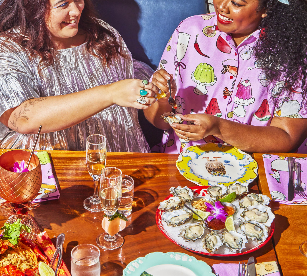 Models angelina and erin eating oysters and wearing metallic top and dinner party print