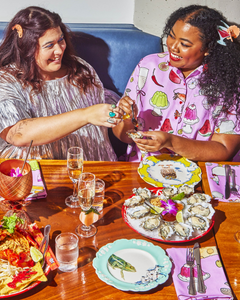 Models angelina and erin eating oysters and wearing metallic top and dinner party print